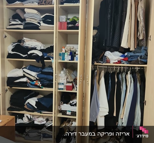 ארון בגדים פתוח עם בגדים מקופלים ותלויים, נעליים על המדף התחתון.